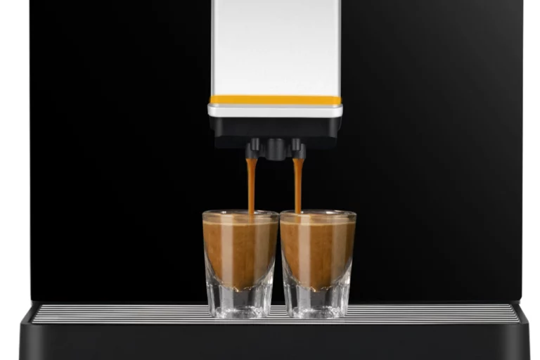 A straight-on, close-up shot of an espresso machine dispensing two rich, dark brown shots of espresso simultaneously into two small, clear glass espresso cups.